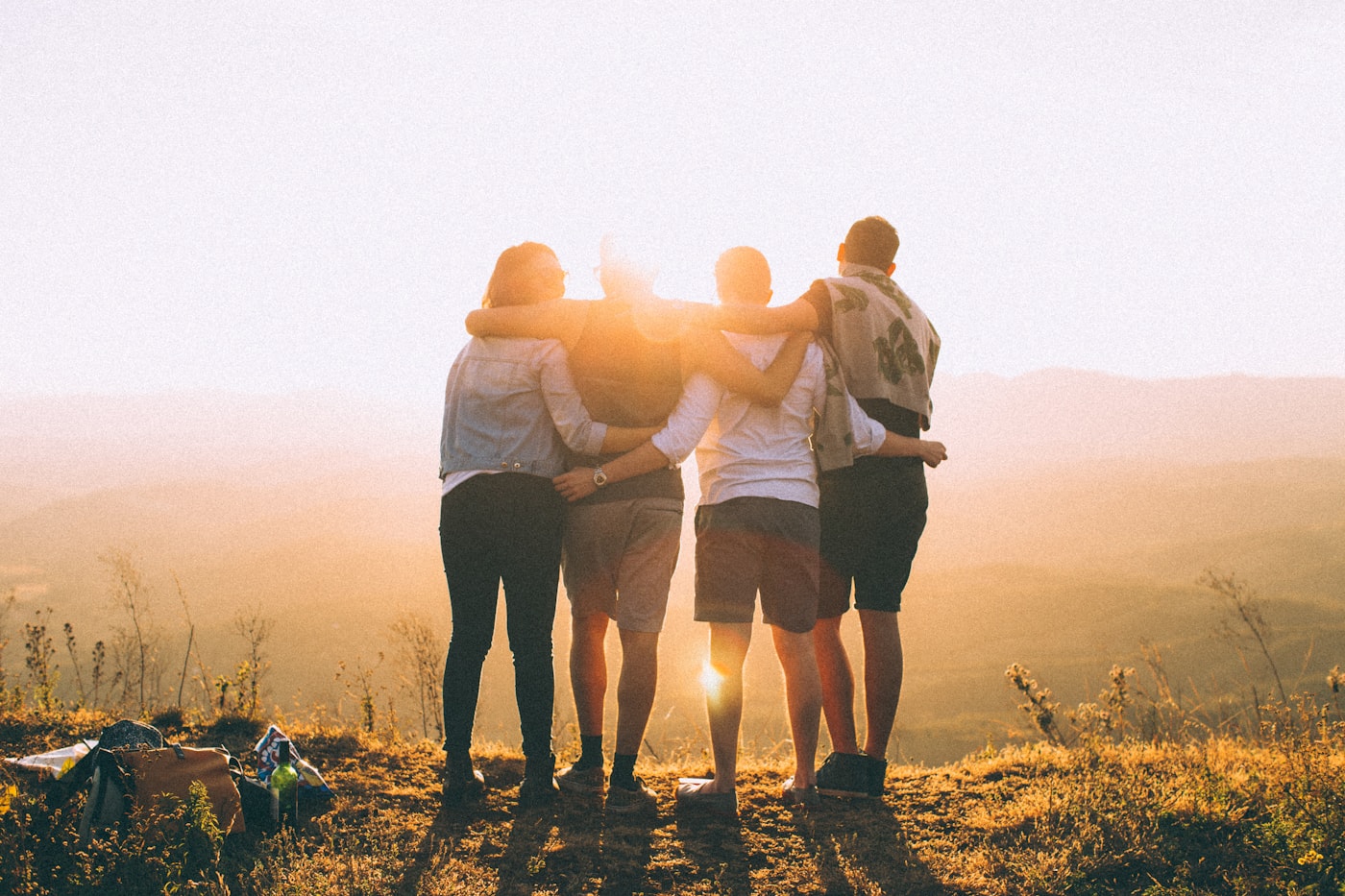 Four friends standing together at sunset